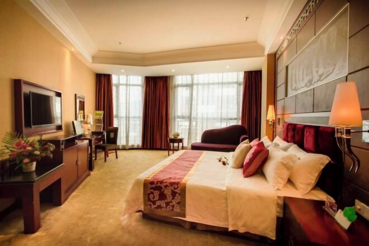 Une chambre d’hôtel avec un lit, une télévision, un bureau et une chaise.