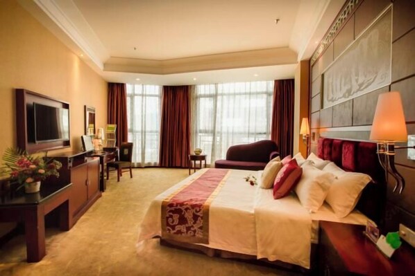 Una habitación de hotel con cama, televisión, escritorio y silla.