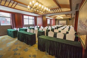 A conference room with rows of tables and chairs, large windows, and a chandelier. - Golden Lusheng International Hotel (Rongshui)