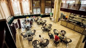 A spacious dining area with multiple tables and chairs, a buffet setup, and a balcony with a railing. - Golden Lusheng International Hotel (Rongshui)