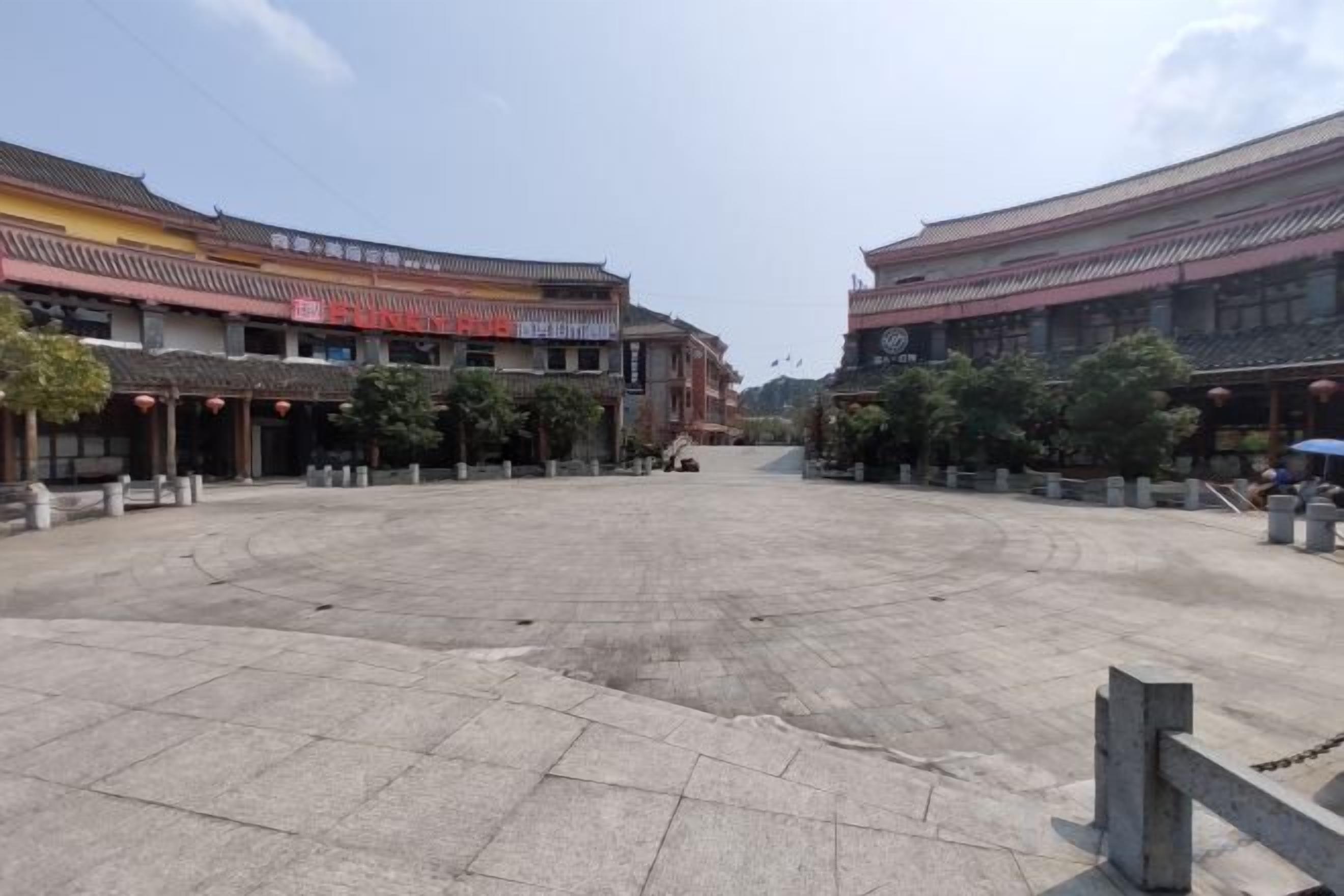 A courtyard with traditional architecture, a central open space, and buildings with signage.