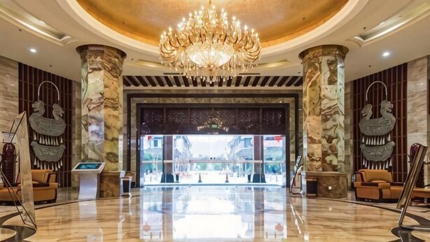 A lobby with a chandelier, marble columns, and a reception desk. - Golden Lusheng International Hotel (Rongshui)