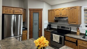 A kitchen with wooden cabinets, stainless steel appliances, and a granite countertop. - 3 Bedrooms - Main Floor of House (Edmonton)
