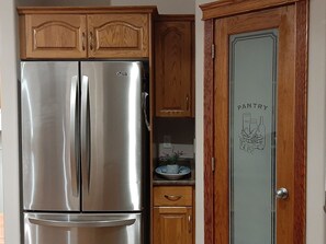 A stainless steel refrigerator in a kitchen with wooden cabinets and a pantry door. - 3 Bedrooms - Main Floor of House (Edmonton)