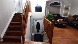 A staircase leading to a laundry room with a washing machine and dryer, a wooden railing, and a black leather sofa in the living area. - 3 Bedrooms - Main Floor of House (Edmonton)