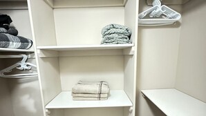 A walk-in closet with white shelves, a hanging rod, and a wooden floor. - 3 Bedrooms - Main Floor of House (Edmonton)