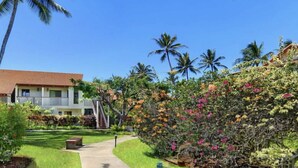 A hotel with a red-tiled roof, white exterior walls, and a white fence. There are palm trees and flowering plants in the garden. - KAUAI BEST DEAL!!!!   1-10-25 thru 1-17-25    - Sleeps 8 (Koloa)