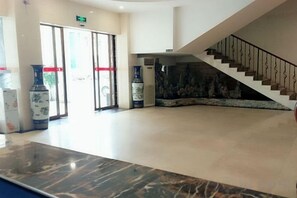 A lobby with a marble reception desk, a staircase, and large vases. - Bishui Lantian Hotel (Funing)