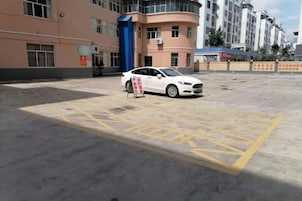 Un estacionamiento con un coche blanco aparcado cerca de un cartel.