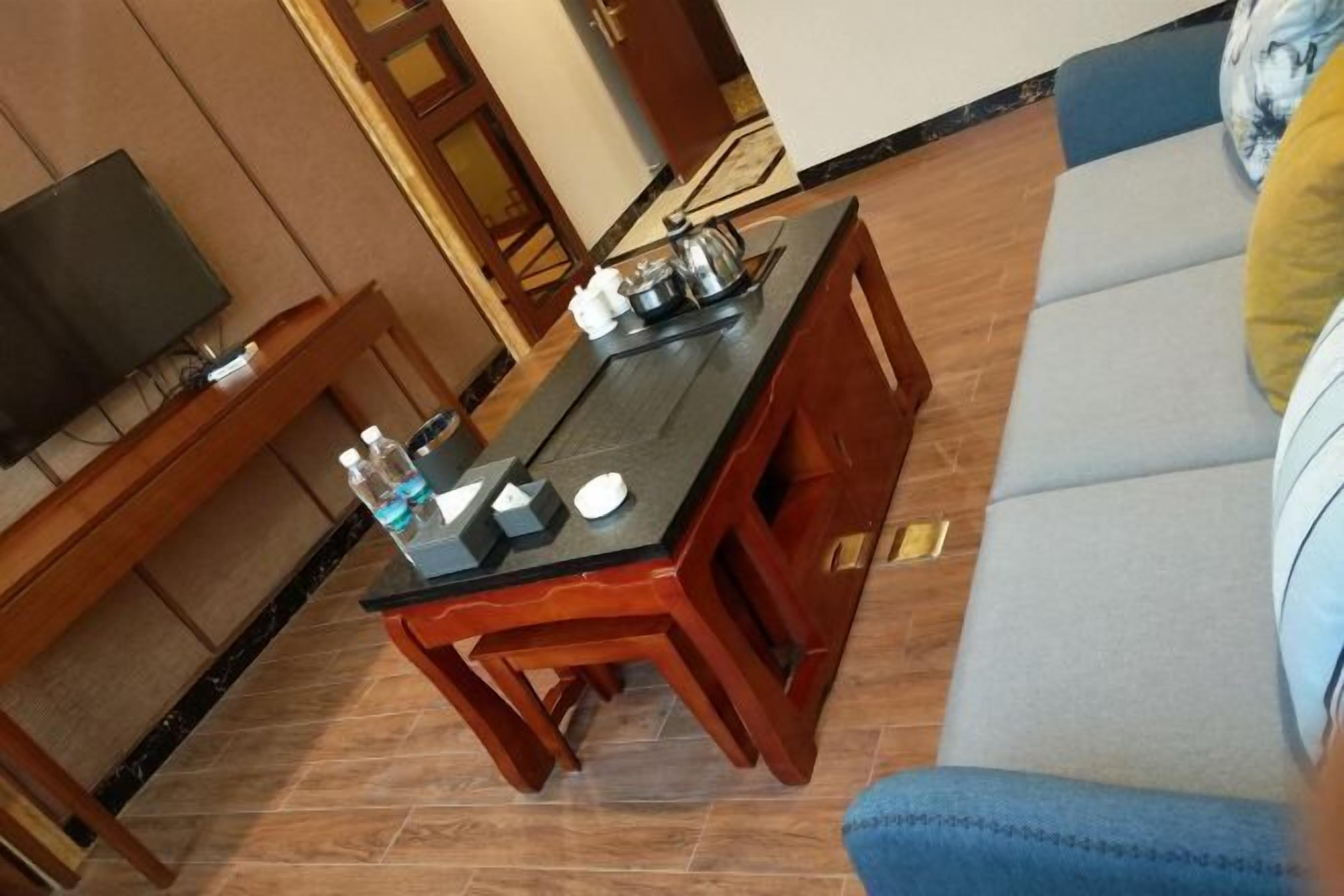 A room with a wooden dining table, a sofa, and a television.