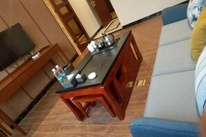 A room with a wooden dining table, a sofa, and a television. - Bishui Lantian Hotel (Funing)