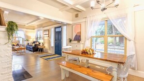 A dining area with a wooden table and benches, a blue door, and a view of the outdoors. - Upgraded Home with 5BR/4Bath/4 FREE gated parking/EV Charger (Seattle)