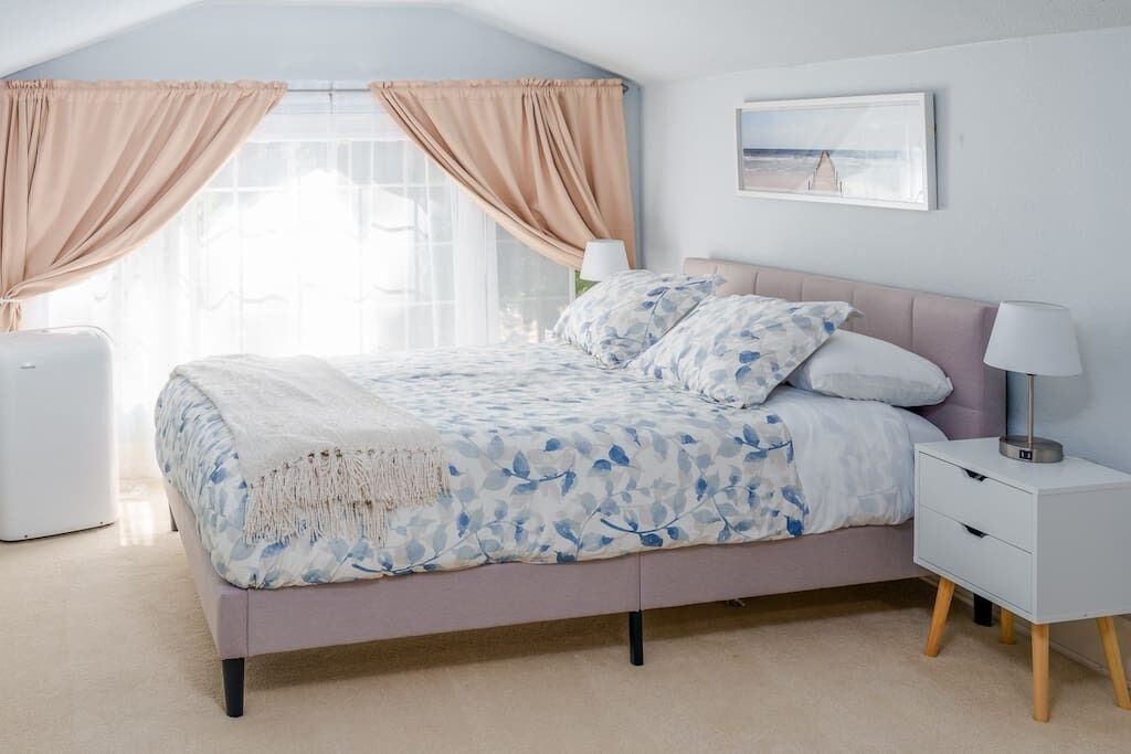 A bedroom with a bed, bedside table, lamp, and a painting on the wall.