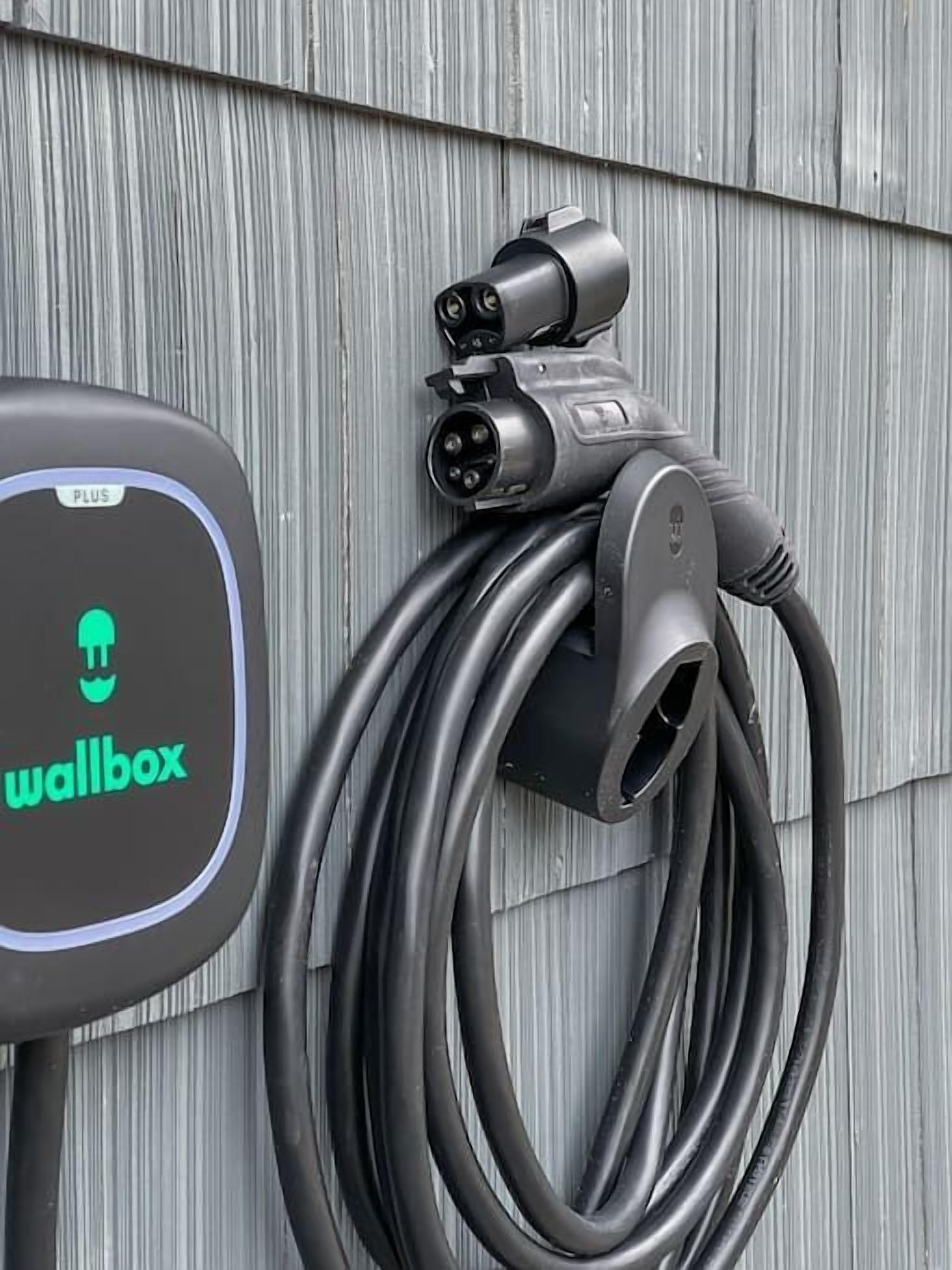 Uma wallbox com um logotipo verde e um cabo de carregamento conectado.