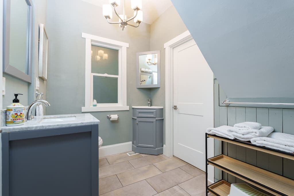 A bathroom with a sink, mirror, vanity, and a towel rack.
