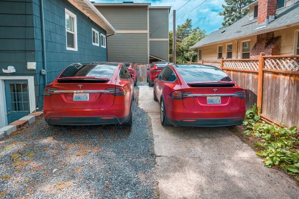 Une allée menant à une maison, avec deux voitures rouges garées.