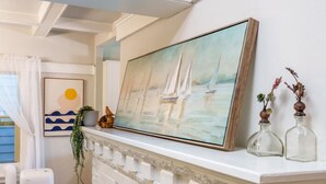 A white fireplace mantel with a framed painting of sailboats, a small plant, and two glass bottles. - Upgraded Home with 5BR/4Bath/4 FREE gated parking/EV Charger (Seattle)