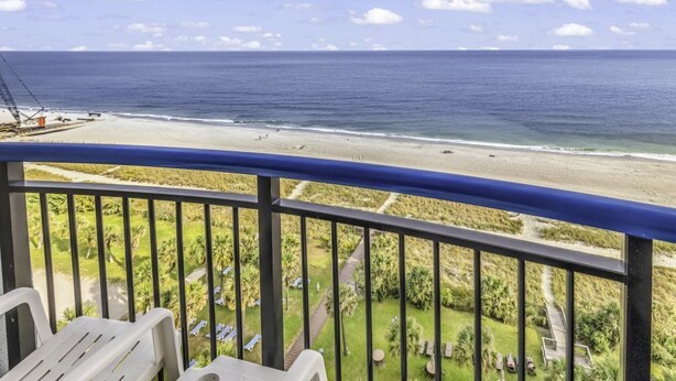 Un balcón con vista a una playa y un campo de golf.