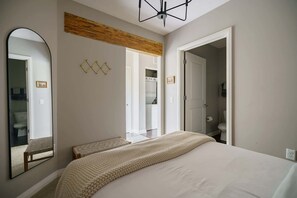 Une chambre avec un grand lit, un miroir, un plafond en bois et une vue sur la salle de bain.