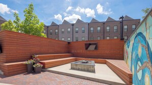 A courtyard with a fire pit, seating area, and a mural on the wall.