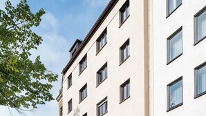 Ein mehrstöckiges Hotel mit moderner Fassade, zahlreichen Fenstern und einem Parkplatz für Autos und Fahrräder.