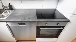 A modern kitchen with a built-in dishwasher, oven, and a black induction cooktop.