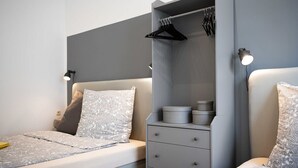A modern bedroom with a bed, bedside tables, and a built-in wardrobe with hanging space.