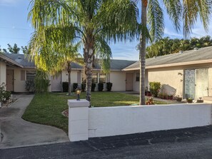 Stunning home with a well-manicured lawn and mature trees, featuring a single-story house with a front porch.