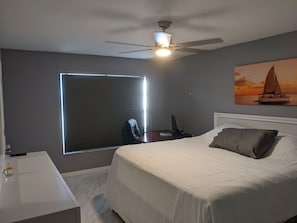 Enjoy a restful stay in this cozy room featuring a large bed, desk, and ceiling fan.
