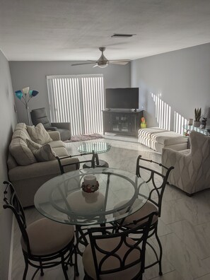 Relax in this stylish living room with a glass-top dining table, flat-screen TV, and comfortable sofa.