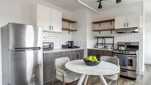 A modern kitchen with stainless steel appliances, white cabinetry, and a marble countertop. - Reside Seattle Downtown, a Wyndham Residence (Seattle)