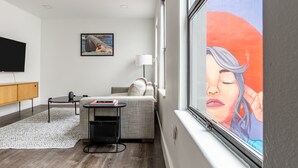 A modern living room with a sofa, a small table, a TV, and a painting on the wall. - Reside Seattle Downtown, a Wyndham Residence (Seattle)