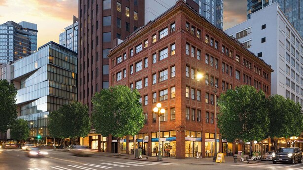 A multi-story building with a classic brick facade, large windows, and a prominent corner location. - Reside Seattle Downtown, a Wyndham Residence (Seattle)