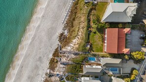 An aerial view of a coastal property with a beach, a swimming pool, and a building with a red roof. - Capistrano E101. Gulf Front, Direct private beach access, Pet Friendly. (Seacrest)
