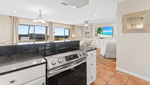 A modern kitchen with a large island, built-in oven, and a view of the ocean through large windows. - Capistrano E101. Gulf Front, Direct private beach access, Pet Friendly. (Seacrest)