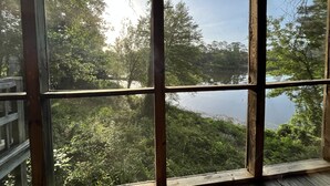 A view from a window overlooking a lake surrounded by dense trees.