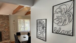 A dining area with a white table and chairs, a fireplace, and decorative wall art with abstract designs and the words 'GATHER here' and 'Relax'. - LAKE FRONT GUESTHOUSE (Columbia)