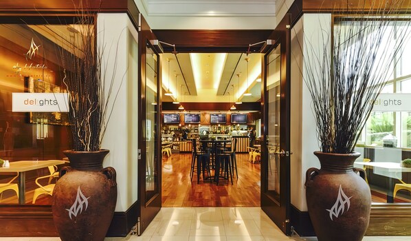A hotel lobby with a reception desk, seating area, and a view into the dining area.