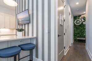 A kitchen with a TV, striped wall, and a plant.