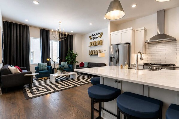A modern kitchen with a central island, stainless steel appliances, and a bar stool seating area.