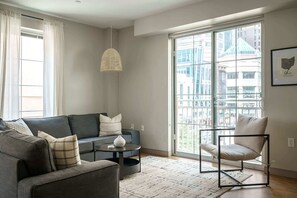 A modern living room with a grey sofa, a round coffee table, a floor lamp, and a chair. - Downtown Luxury Apartment on the Columbus Commons (Columbus)