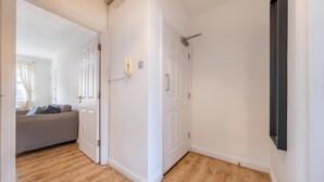 En hall med trägolv, vita väggar och en grå soffa i bakgrunden.