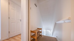 En hall med en träbänk, vita väggar och ett mattbeklätt golv.