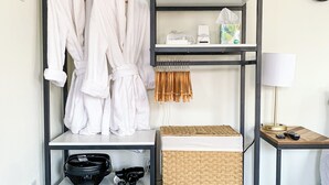 A walk-in closet with shelves for clothes, a basket, and a small table with a lamp. - Washburne Studio: King size comfort and private Hot tub (Springfield)