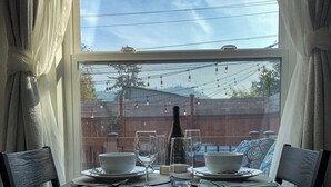 A dining table with chairs, a bottle, and glasses set for two. - Washburne Studio: King size comfort and private Hot tub (Springfield)