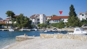 Un port de plaisance situé sur la côte, où plusieurs bateaux sont amarrés, entouré de bâtiments aux toits recouverts de tuiles rouges et de verdure.