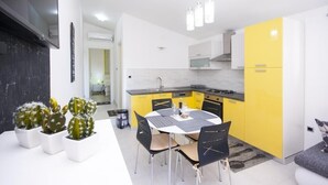 Una cucina moderna con mobili gialli, un tavolo da pranzo bianco e sedie nere.