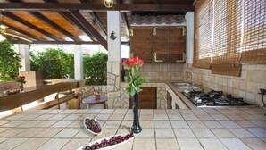 Una cucina con piano di lavoro in pietra, piano cottura a gas e lavello. Sul piano di lavoro c'è un vaso con rose rosse.