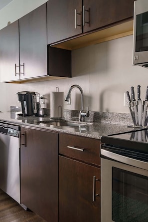 A modern kitchen with dark wood cabinets, stainless steel appliances, and a granite countertop.