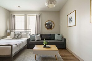 A modern bedroom with a bed, a sofa, a coffee table, and a mirror.